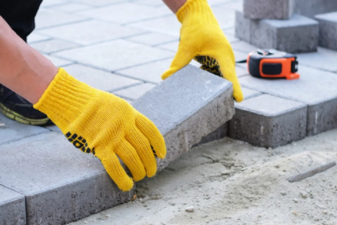 Person verlegt Pflastersteine